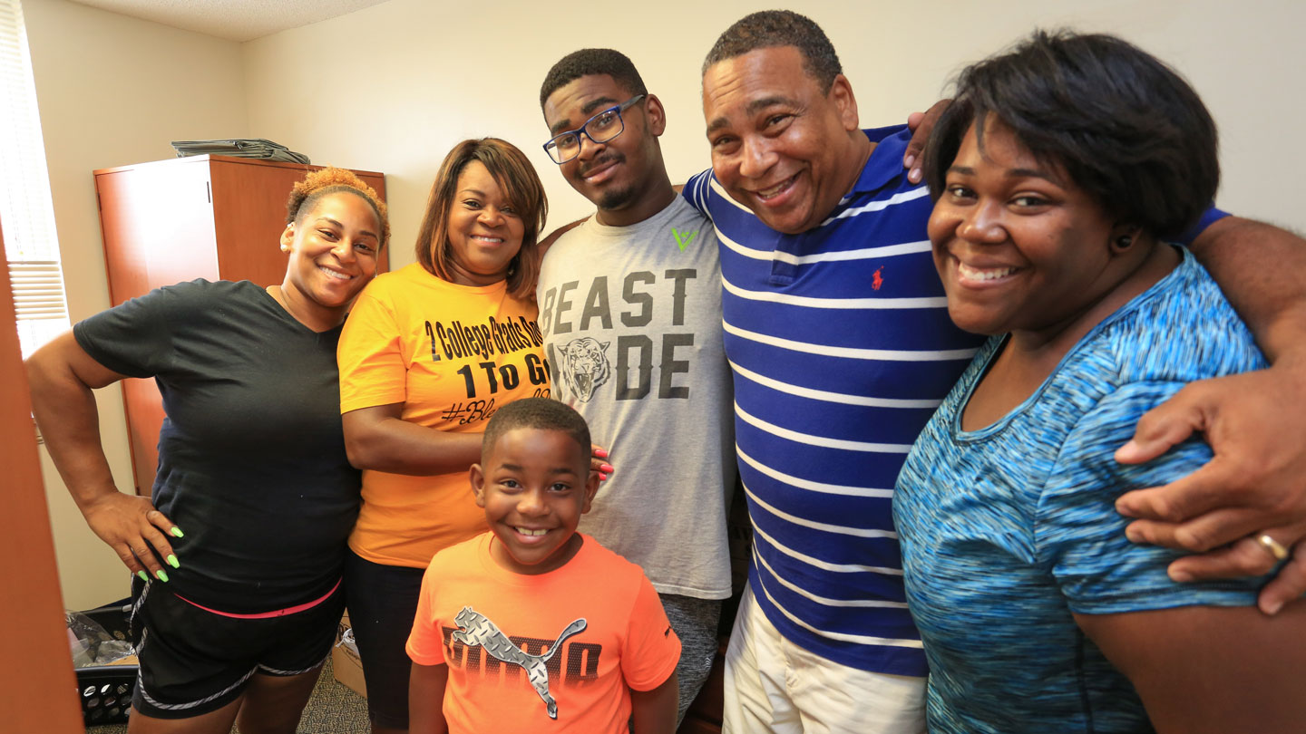 a smiling family helps a college student move into a UAH dormitory room