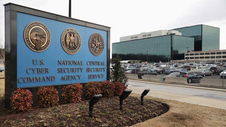 Sign for U.S. Cyber Command, National Security Agency, and Central Security Service with secure government building and parking lot in the background.