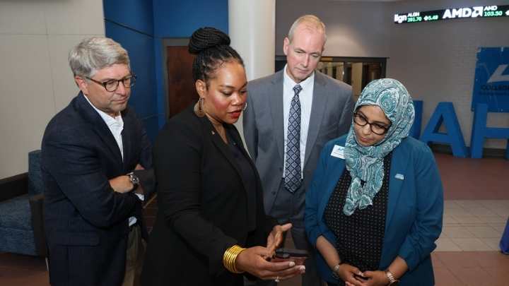 Floresha Watkins demonstrates the Regions Bank app to Dr. Wafa Orman, Associate Dean UAH College of Business. Looking on are Sean Kelly and Dr. Jason Greene