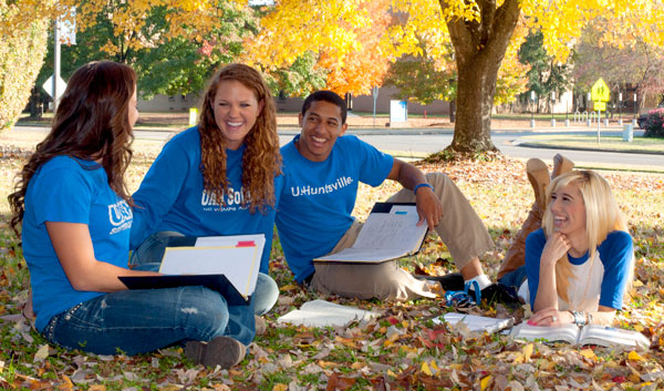 Students enjoying themselves on the campus of UAH under a tree with bright yellow leaves