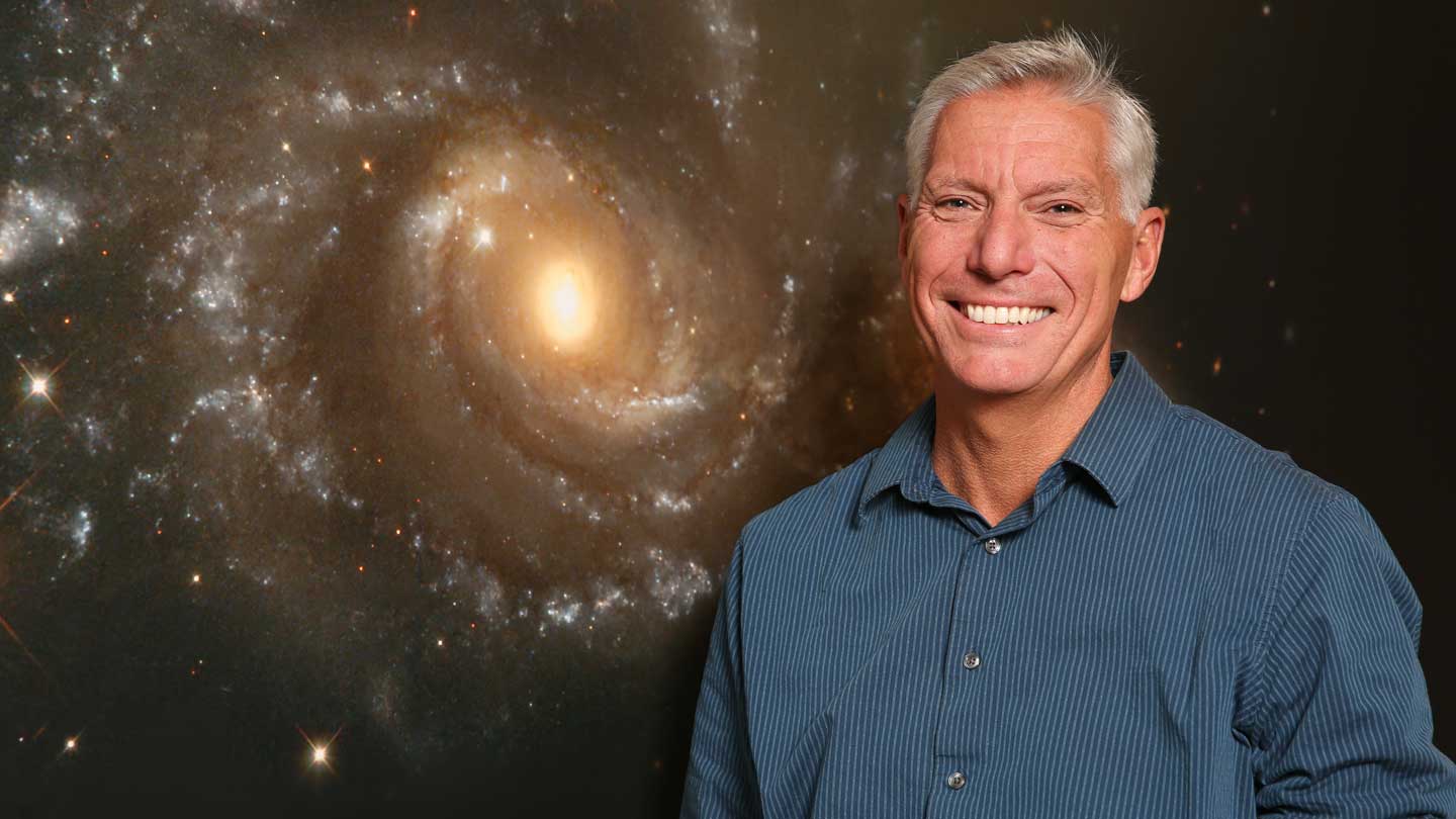 Dr. Gary Zank standing in front of a space background.
