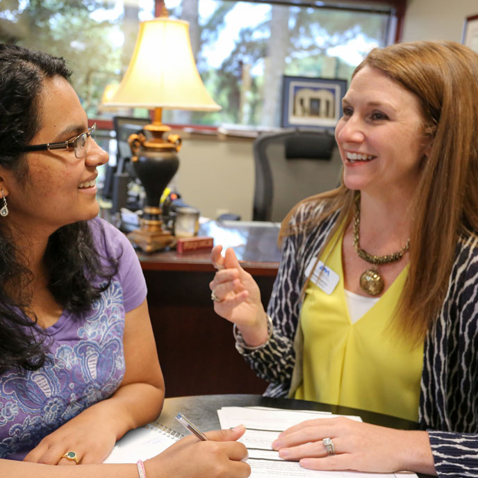 a smiling advisor meets with an eager student