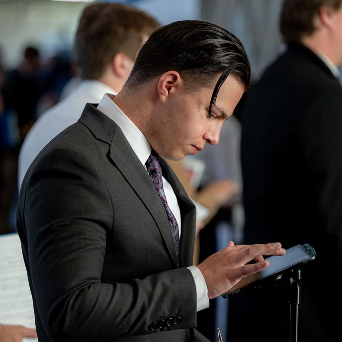 A young man in a suit searches his tablet for job resources