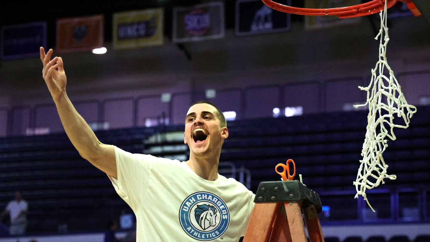 a U A H basketball player celebrates a championship by cutting down a net
