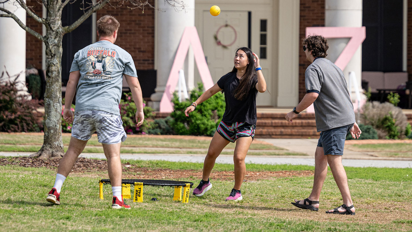 Three students play Spikeball on the lawn of the Delta Zeta sorority house at U A H