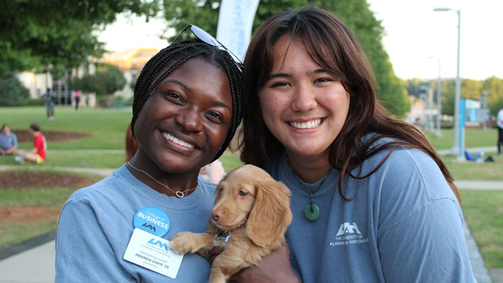 Amanda Davis, left, and Kai Zhang hang out with a furry puppy.