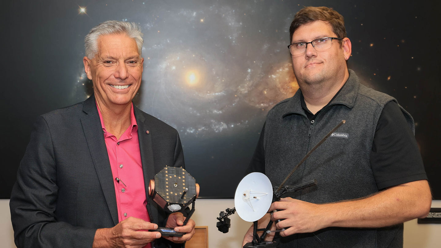 Former UAH student and model maker (right) Blake Parker presents models of the Voyager and Interstellar Boundary Explorer spacecraft to (left) Dr. Gary Zank, director of the Center for Space Plasma and Aeronomic Research