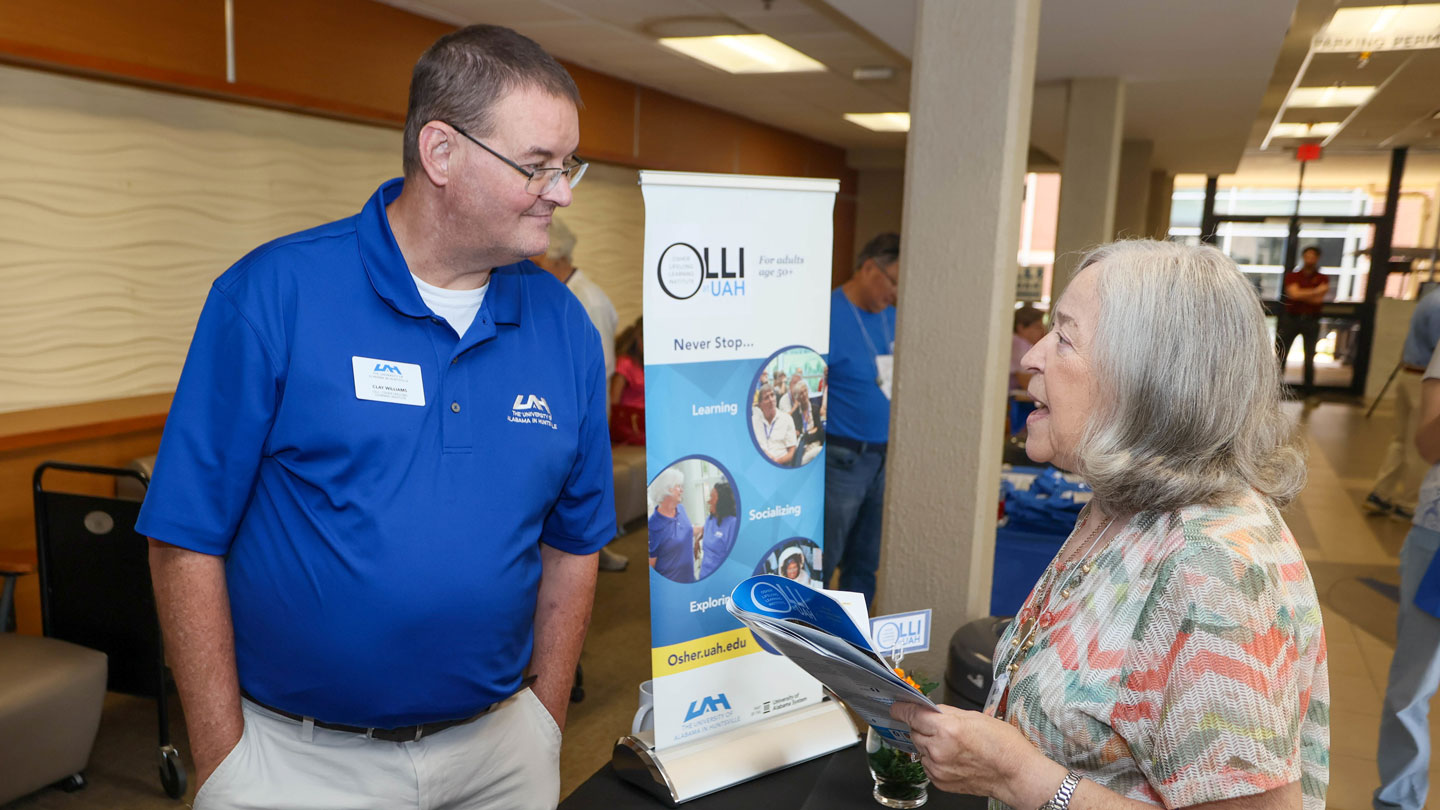 Clay Williams, left, program manager for the Osher Lifelong Learning Institute at The University of Alabama in Huntsville welcomes a guest to the fall 2024 OLLI open house on Aug. 16, 2024