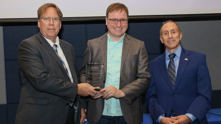 Dr. Bryan Mesmer, center, receives University Distinguished Research, Creative Achievement, and Scholarly Performance Award from Dr. Robert Lindquist, left, vice president for research and economic development, and Provost Dave Puleo